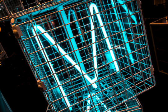 M neon light letter in a metal cage with a dark background
