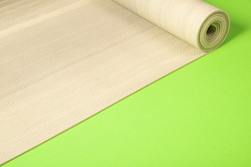 Yoga mat on green background with copyspace.