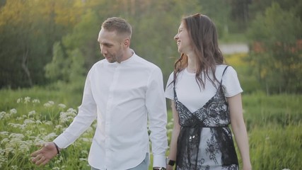 Couple holding hands and walking outdoors. Sunset time.