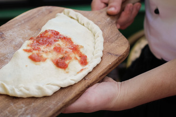 Chief making closed calzone pizza