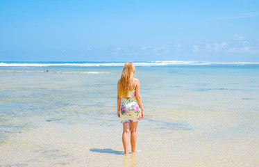 Blonde girl in dress on the background of the ocean on the island of Bali, Indonesia