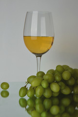 glass of white wine with grapes on a white background