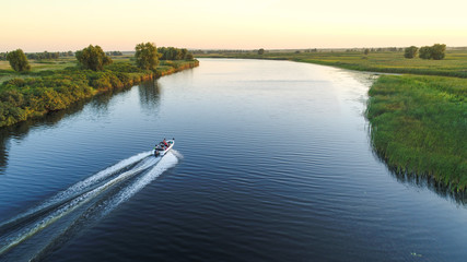 Aerial view of speed boat going on sunset on blue river 