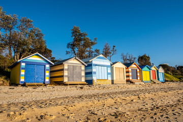 Fototapeta na wymiar Colorful beach huts on the sand of Dromana coastline in Melbourne, Australia