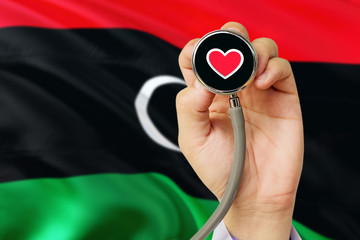 Doctor holding stethoscope with red love heart. National Libya flag background. Healthcare system...