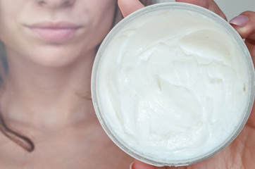 Closeup of young woman's hand holding jar of moisturizing cream in hands
