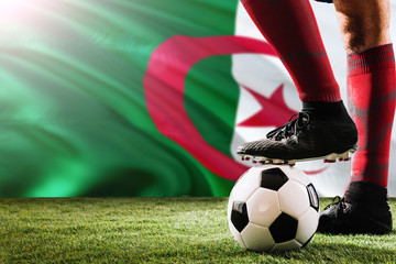 Close up legs of Algeria football team player in red socks, shoes on soccer ball at the free kick...