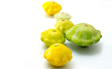 Pattypan squashes vegetable. Group of green and yellow pattypan squashes, on white table background.