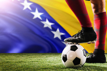 Close up legs of Bosnia Herzegovina football team player in red socks, shoes on soccer ball at the...