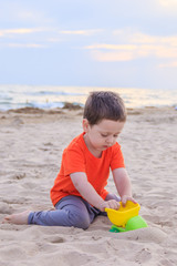 A boy plays a typewriter on the beach. Children's games. Beach in the summer. Small child