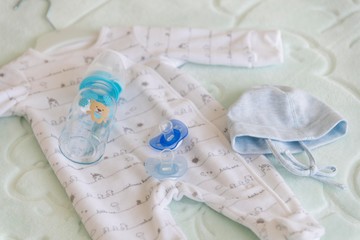 Fototapeta na wymiar baby clothes with milk bottle and baby pacifier