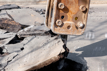 machine drills asphalt. Large fragments of land and pits everywhere on the road. working equipment with a drill works loudly