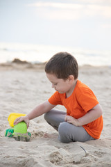 A boy plays a typewriter on the beach. Children's games. Beach in the summer. Small child
