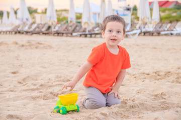 A boy plays a typewriter on the beach. Children's games. Beach in the summer. Small child