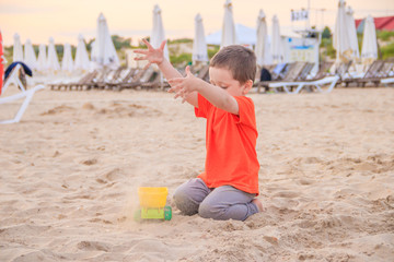 A boy plays a typewriter on the beach. Children's games. Beach in the summer. Small child