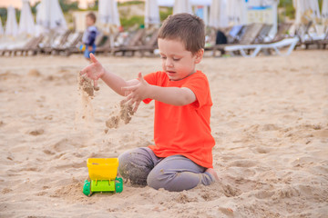 A boy plays a typewriter on the beach. Children's games. Beach in the summer. Small child