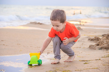 A boy plays a typewriter on the beach. Children's games. Beach in the summer. Small child