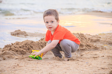 A boy plays a typewriter on the beach. Children's games. Beach in the summer. Small child