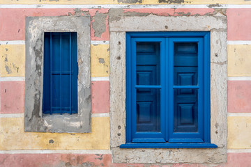 Fototapeta na wymiar Fresh painted wooden window frame shutters in dilapidated house wall