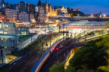 View from above of a train leaving Edinburgh train station at night. Motion blurred. Edinburgh old...