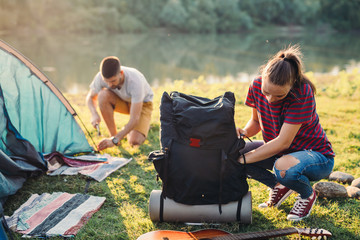 young couple preparing tent for camping by the river