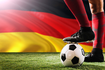 Close up legs of Germany football team player in red socks, shoes on soccer ball at the free kick or penalty spot playing on grass.