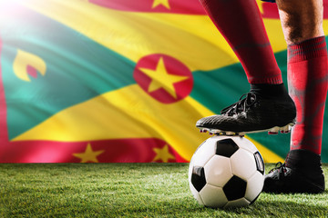 Close up legs of Grenada football team player in red socks, shoes on soccer ball at the free kick...