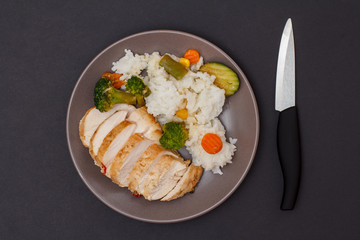 Baked chicken breasts or fillet on plate with rice and vegetables on plate.