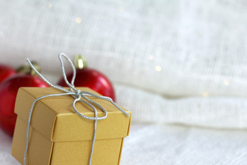 golden box with a silver ban on the background of red balls to decorate the Christmas tree. gift for christmas greetings
