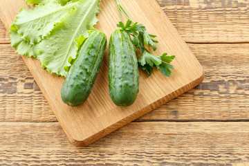 Just picked cucumbers and leaves of salad lying on cutting board.