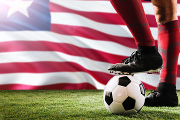 Close up legs of Liberia football team player in red socks, shoes on soccer ball at the free kick...