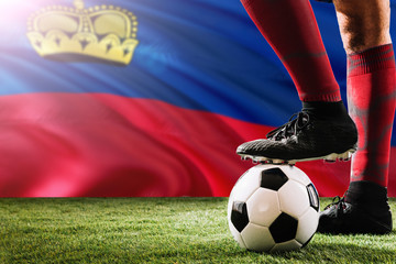 Close up legs of Liechtenstein football team player in red socks, shoes on soccer ball at the free...