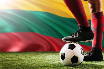 Close up legs of Lithuania football team player in red socks, shoes on soccer ball at the free kick...