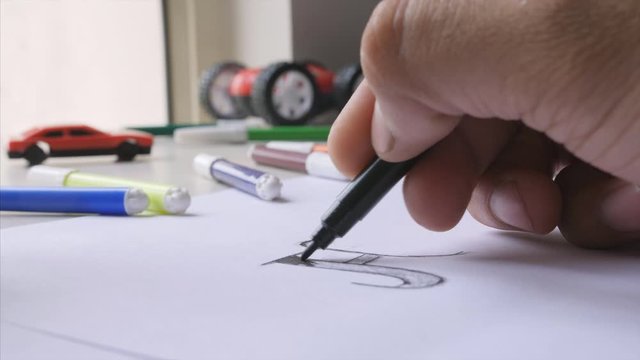 Closeup shot of man / boy colouring the alphabet with black sketch pen. 