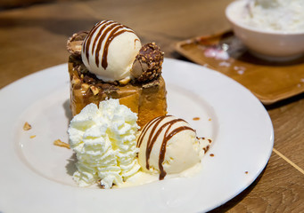 honey toast with vanilla ice cream and whiping cream topped with chocolate sauce on white dish. sweets bread and dessert. high calories from sugar. image for background, wallpaper and copy space.