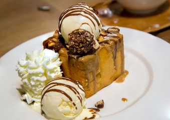 honey toast with vanilla ice cream and whiping cream topped with chocolate sauce on white dish. sweets bread and dessert. high calories from sugar. image for background, wallpaper and copy space.