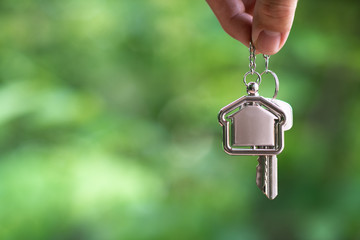 Home key with house keyring hanging with white wall background