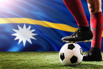 Close up legs of Nauru football team player in red socks, shoes on soccer ball at the free kick or...