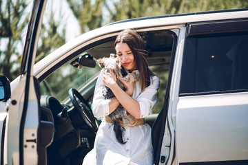 Very beautiful girl with a pretty dog near a luxury car