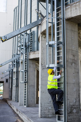 worker in safety equipment climbing on industrial ladders © cherryandbees