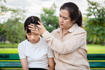 Asian girl has discomfort and headache,mother touching forehead of child girl,checking the temperature,caring mom takes care of her sick daughter,high fever symptoms,medical and health care concept
