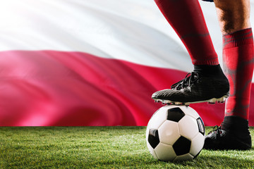 Close up legs of Poland football team player in red socks, shoes on soccer ball at the free kick or...