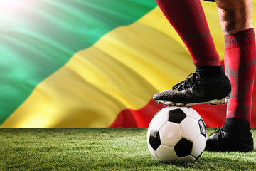 Close up legs of Republic Of The Congo football team player in red socks, shoes on soccer ball at...