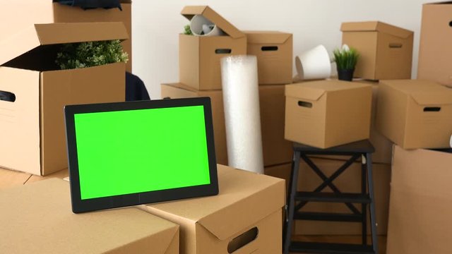 Closeup on a tablet with green screen among cardboard boxes
