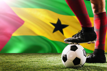 Close up legs of Sao Tome And Principe football team player in red socks, shoes on soccer ball at...