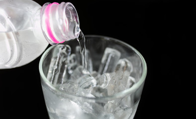 Glass ice isolated on black table. Cool water.