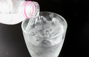 Glass ice isolated on black table. Cool water.