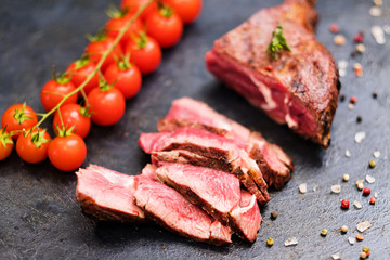 Steakhouse menu. Cowboy steak. Sliced medium grilled beef meat, cherry tomatoes and mixture of peppers.