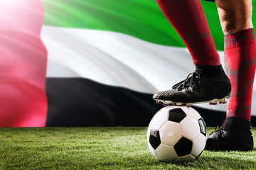 Close up legs of United Arab Emirates football team player in red socks, shoes on soccer ball at...