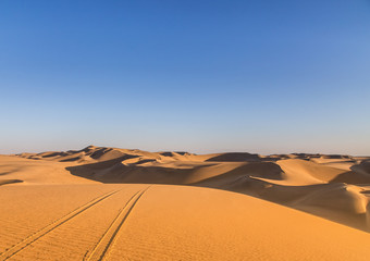 Naklejka na ściany i meble Sand dunes in the desert with vehicle track